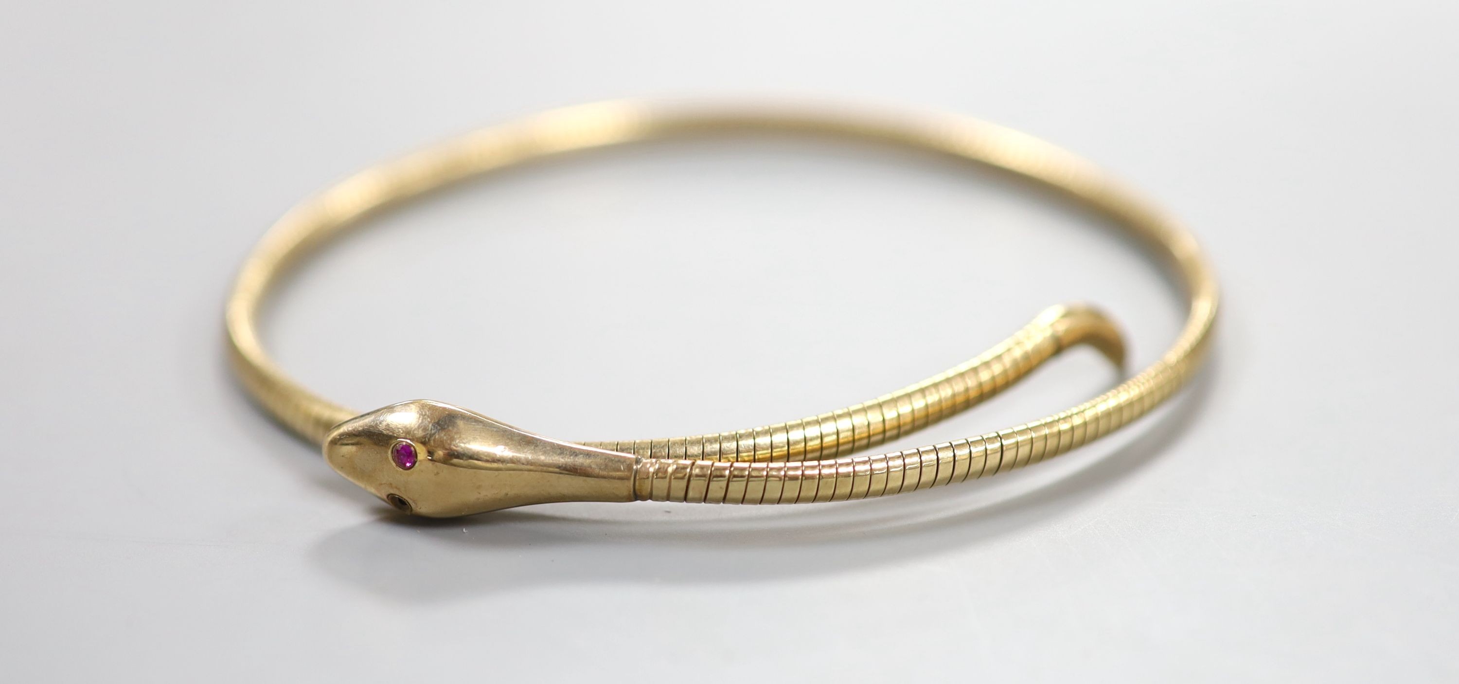 An early to mid 20th century 9ct coiled serpent bracelet, with gem set eyes (one missing), gross 15.4 grams.